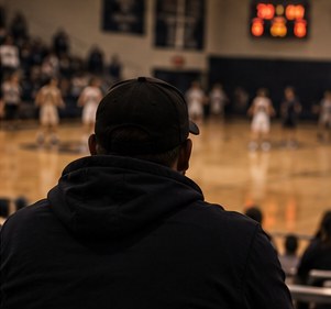 A parent watching a high school basketball game from the stands
